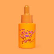 Studio photograph of HotChi’s Bring Your Fire Facial Oil bottle on a vibrant orange background, symbolising its calming and anxiety-soothing effects.