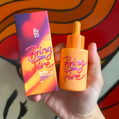 A hand holding the Bring Your Fire Facial Oil bottle, symbolizing self-care and calmness with HotChi's mood-boosting skincare.