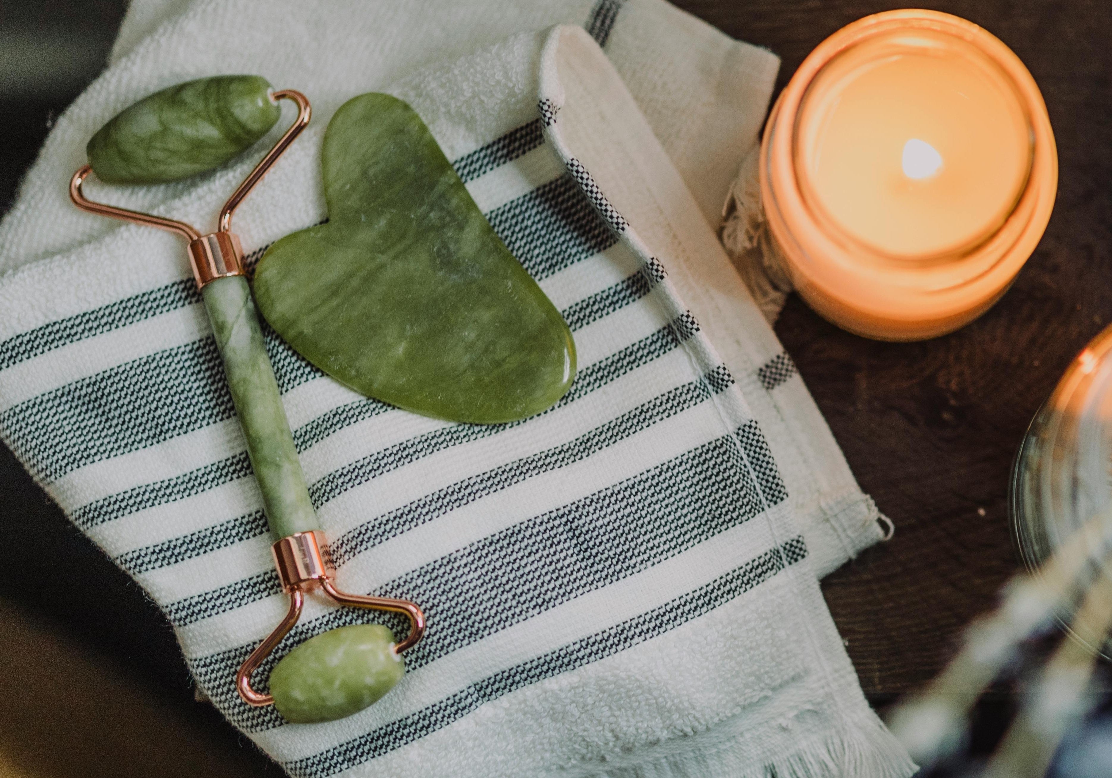 Jade Roller and a Gua Sha near a relaxing candle