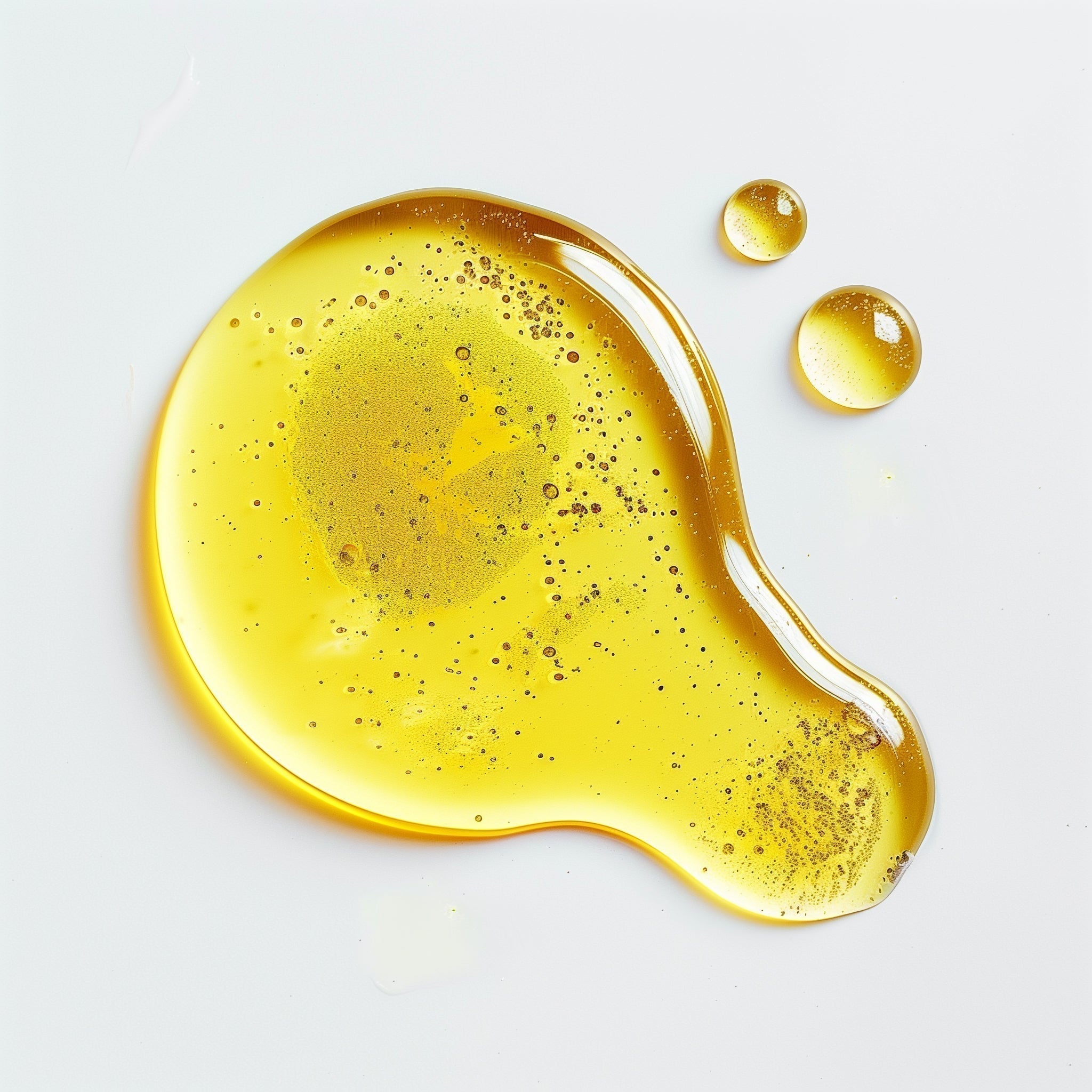 Facial oil texture shown in close-up detail on a clean white background, highlighting its smooth, lightweight consistency and natural golden sheen.
