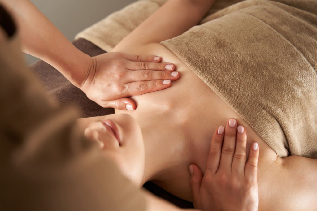 Woman receiving a chest massage using HotChi facial oil, showcasing a calming self-acupressure ritual with HotChi Mood Boosting Oils.