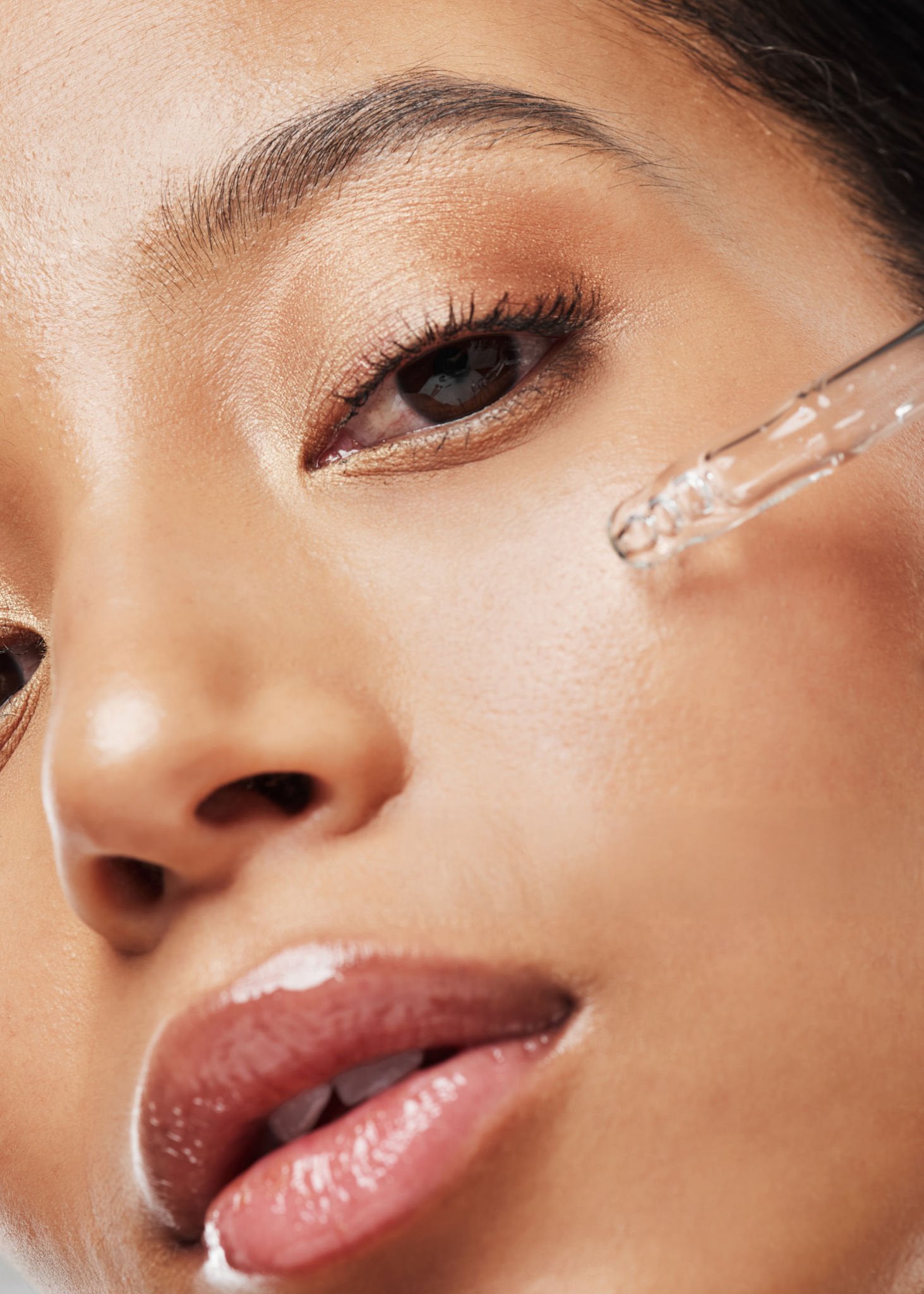 Close-up of a woman applying facial oil to her face, highlighting smooth skin and a calming skincare ritual.