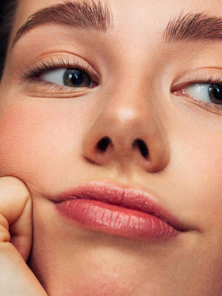Close-up of a woman’s face with glowing, healthy skin, highlighting natural texture and radiance.