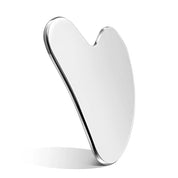 Angled view of a stainless steel gua sha highlighting its polished finish and ergonomic design for sculpting and tension relief.