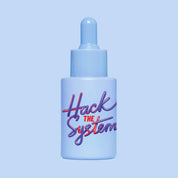 Studio shot of HotChi’s Hack The System Facial Oil bottle against a blue background, highlighting its energising design and focus-enhancing benefits.