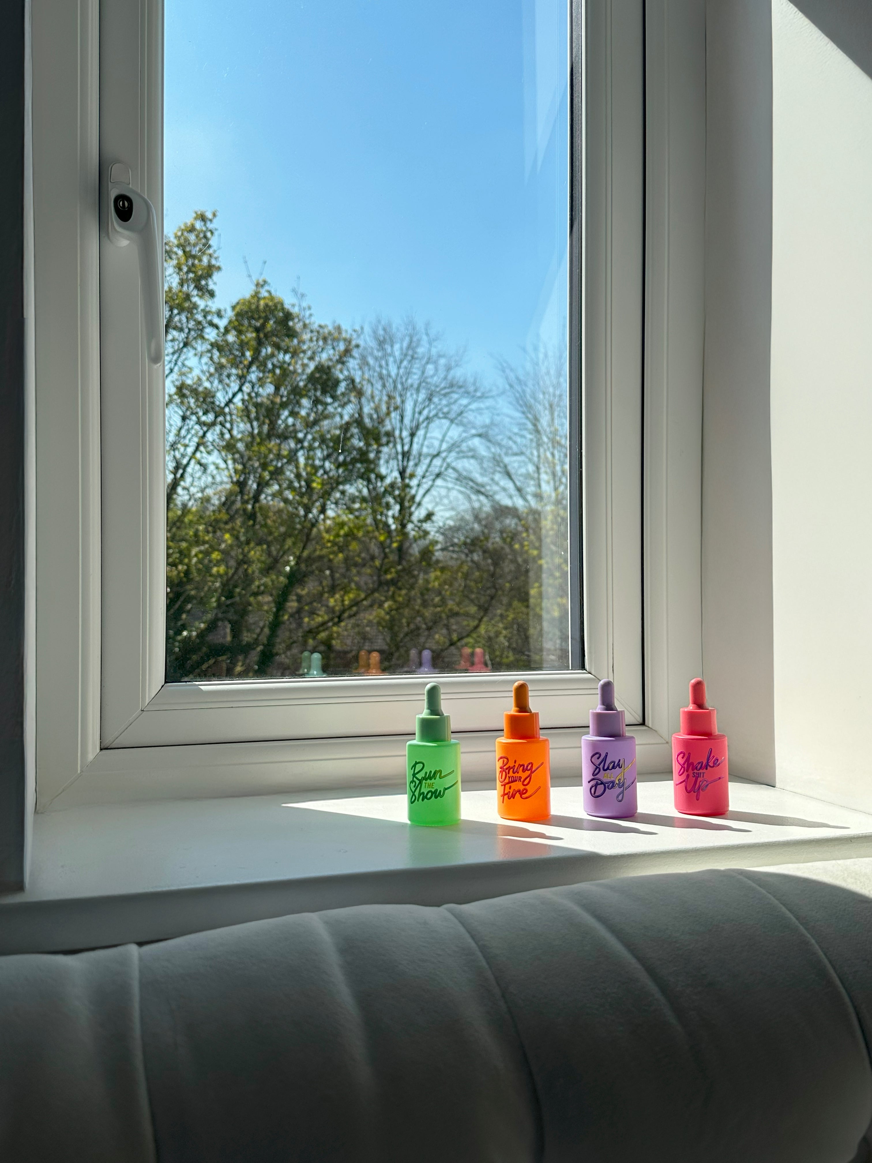 Four HotChi skincare products displayed near a window with soft natural light and nature background