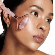 Woman gliding dual pink jade rollers upward along her jawline, demonstrating a balanced and soothing skincare massage.