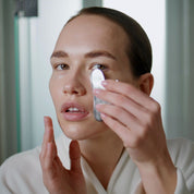 Close-up of a white woman using a stainless steel gua sha on her cheek, highlighting a soothing skincare ritual.