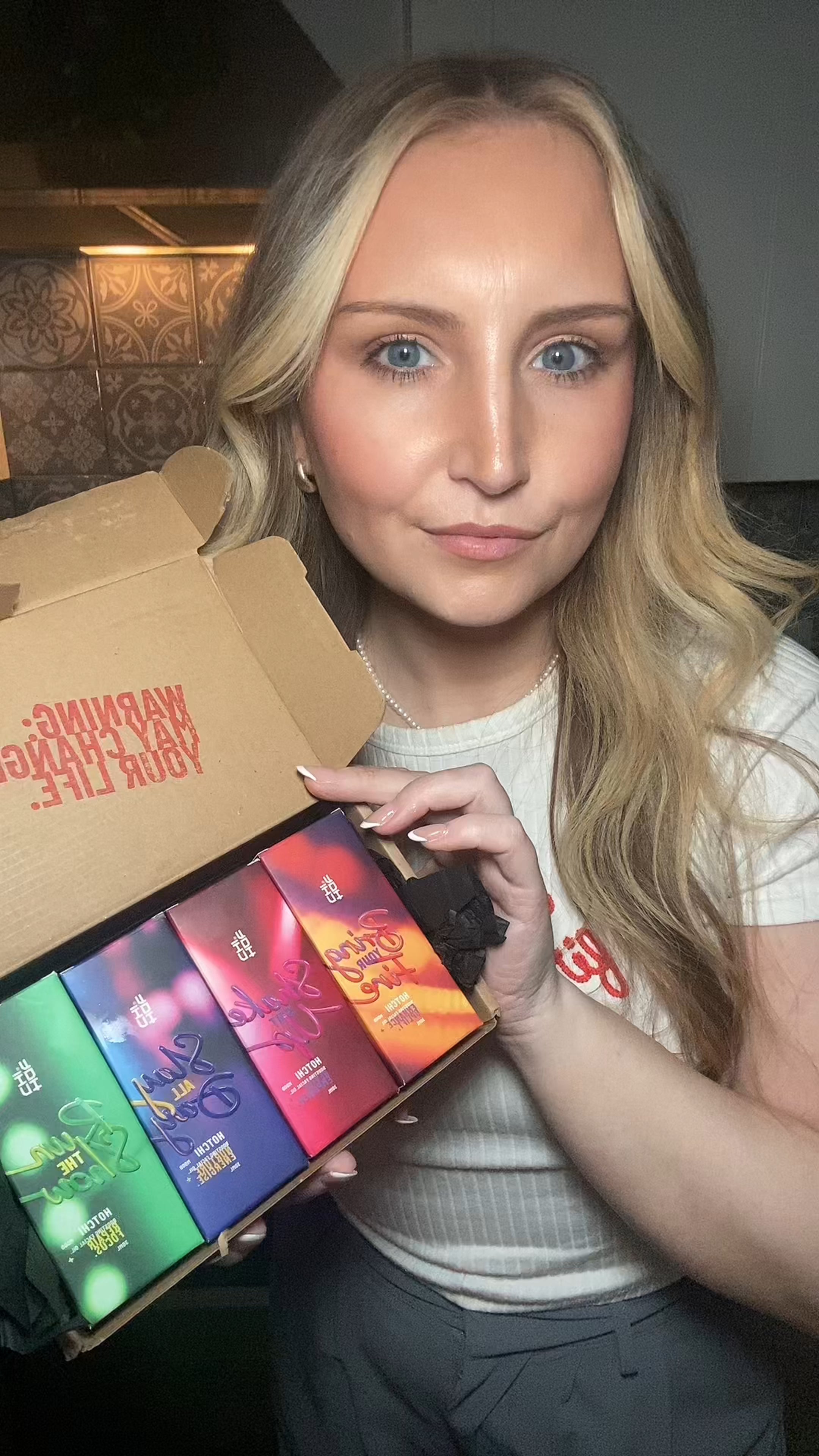 Woman holding the full HotChi skincare collection and smiling